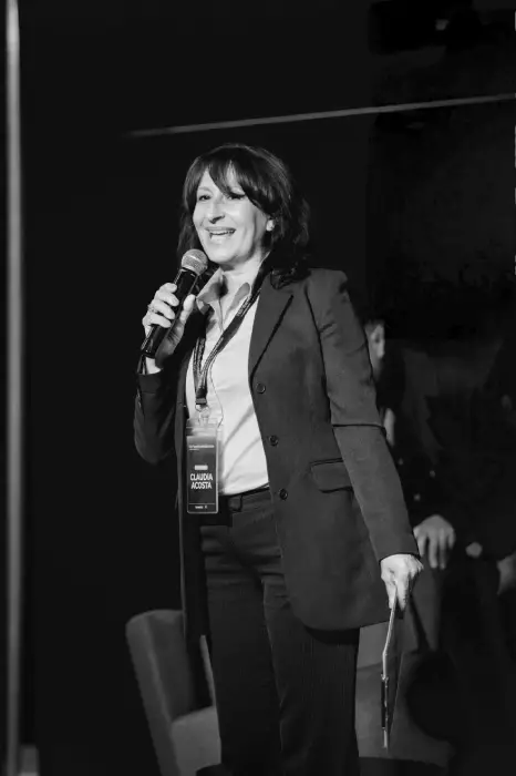 Claudia Acosta con micrófono moderando en vivo